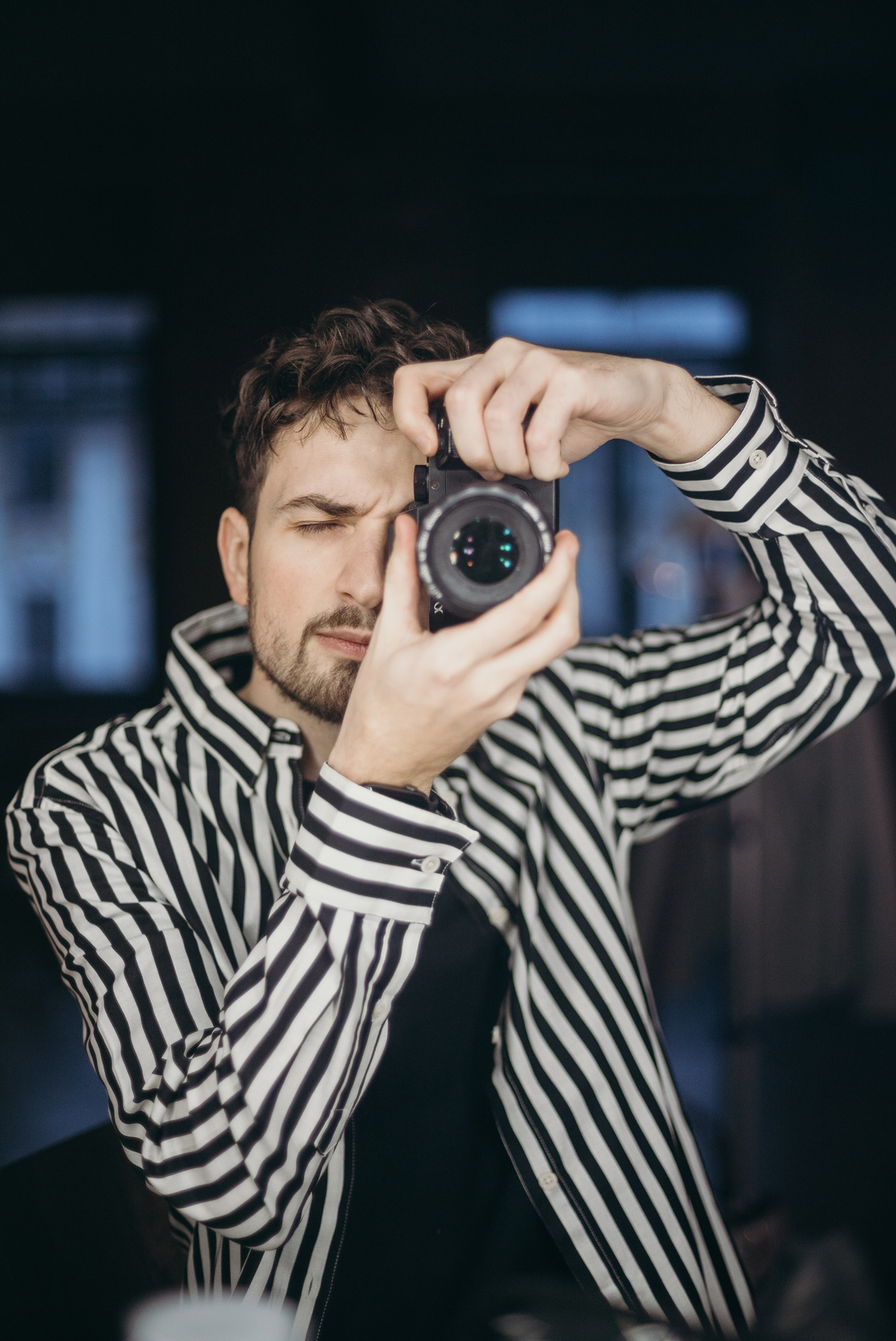 Man In Black And White Striped Long Sleeve Shirt Holding Black Camera